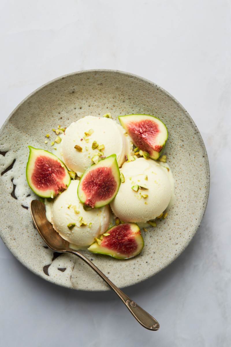 Finished ice cream served with fresh figs and pistachios on a ceramic plate